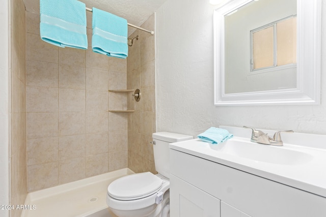 bathroom with vanity, tiled shower, a textured ceiling, and toilet