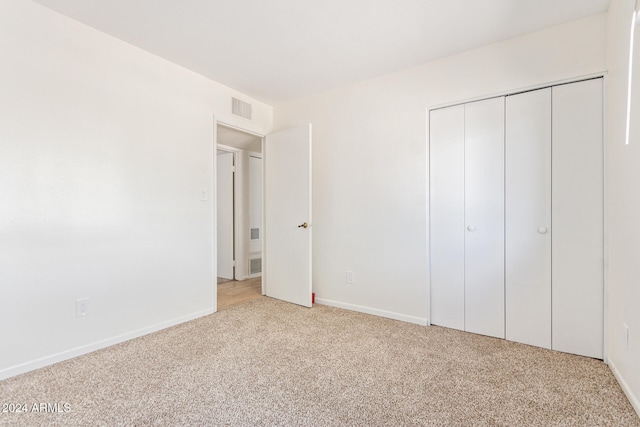 unfurnished bedroom with light colored carpet and a closet