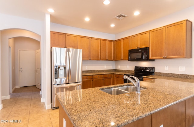 kitchen featuring light stone countertops, black appliances, sink, and light tile patterned floors