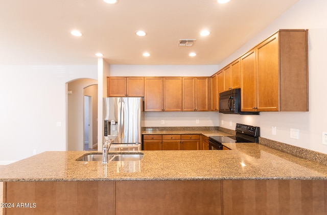 kitchen with sink, black appliances, light stone countertops, and kitchen peninsula