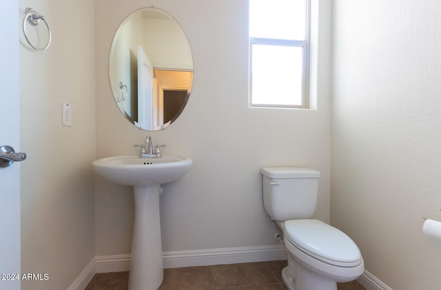 bathroom with toilet, sink, and tile patterned flooring