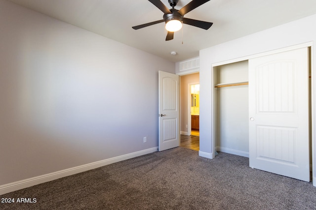 unfurnished bedroom featuring dark colored carpet, a closet, and ceiling fan