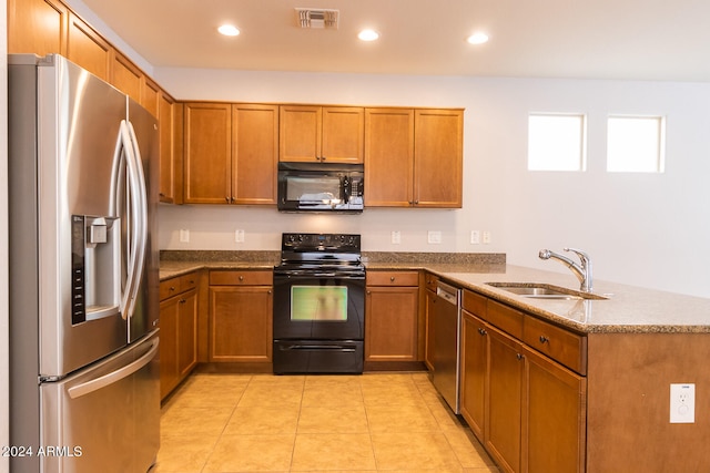 kitchen with kitchen peninsula, light tile patterned flooring, black appliances, stone counters, and sink