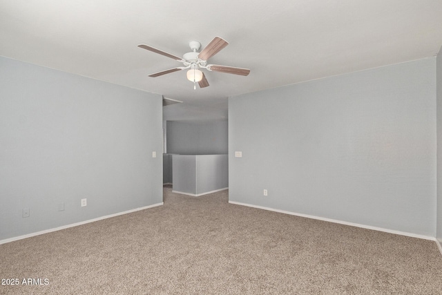 carpeted spare room featuring baseboards and a ceiling fan