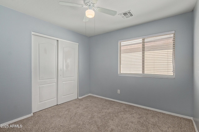 unfurnished bedroom featuring baseboards, visible vents, a closet, and light colored carpet