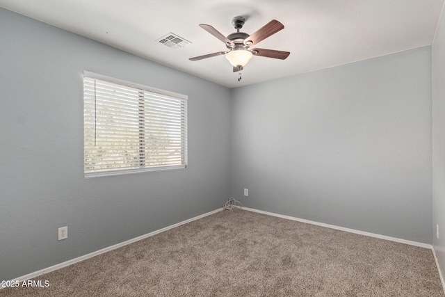 empty room featuring ceiling fan, carpet floors, visible vents, and baseboards