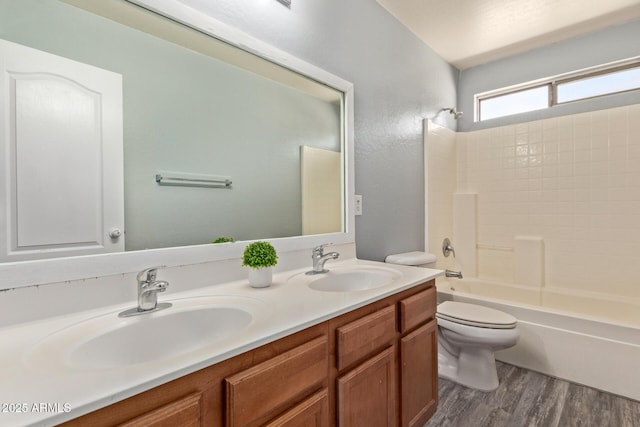 full bathroom featuring wood finished floors, shower / bathing tub combination, a sink, and toilet