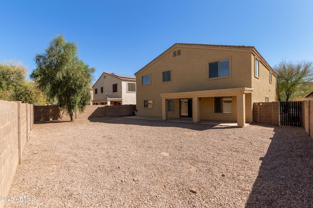 back of property with a fenced backyard, a patio, and stucco siding