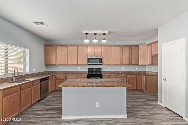 kitchen featuring brown cabinets, visible vents, appliances with stainless steel finishes, a sink, and a kitchen island