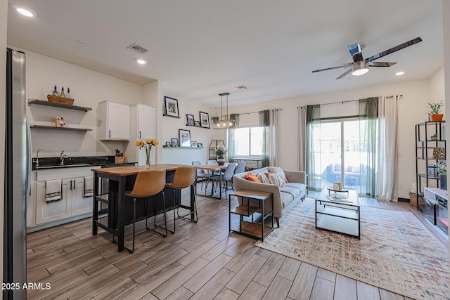 living room with wood tiled floor, ceiling fan, visible vents, and recessed lighting