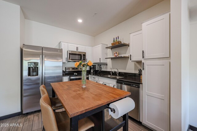 kitchen featuring a sink, open shelves, butcher block countertops, stainless steel appliances, and white cabinets