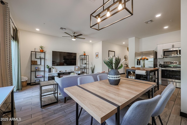 dining area with wood tiled floor, recessed lighting, ceiling fan with notable chandelier, and visible vents