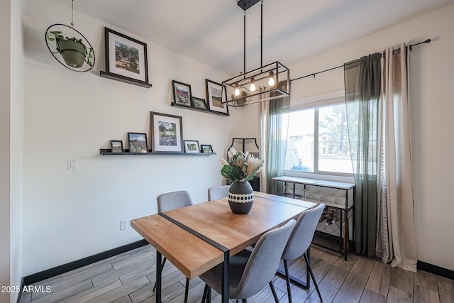 dining space with baseboards, wood tiled floor, and a chandelier