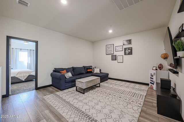 living room featuring baseboards, visible vents, and light wood-style flooring