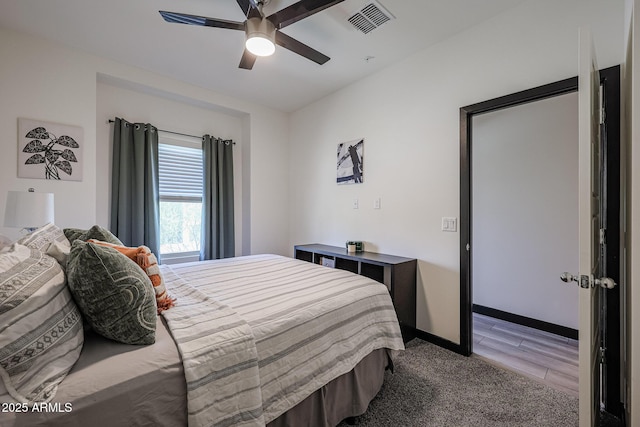 bedroom featuring baseboards, visible vents, a ceiling fan, and wood finished floors