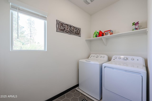 laundry area featuring baseboards, washing machine and dryer, laundry area, and dark tile patterned flooring