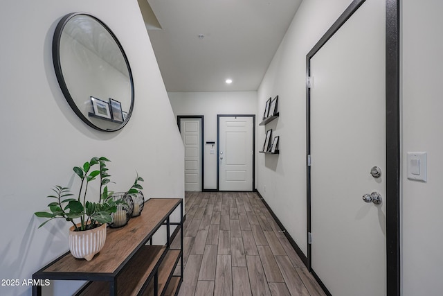 hallway featuring baseboards, wood tiled floor, and recessed lighting