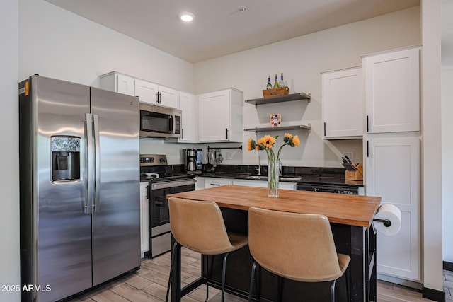 kitchen with white cabinetry, a sink, stainless steel appliances, and open shelves