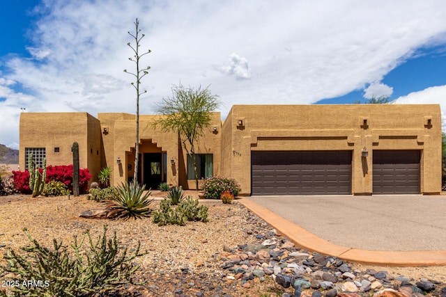adobe home featuring a garage, stucco siding, and driveway