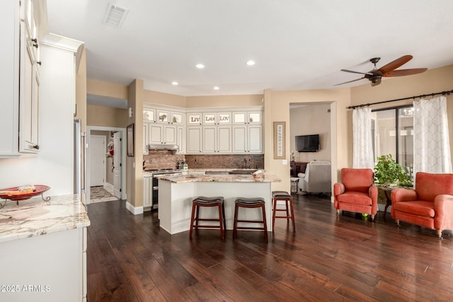 kitchen with range with two ovens, open floor plan, recessed lighting, under cabinet range hood, and visible vents