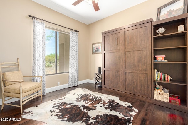 living area featuring ceiling fan, dark wood finished floors, and baseboards