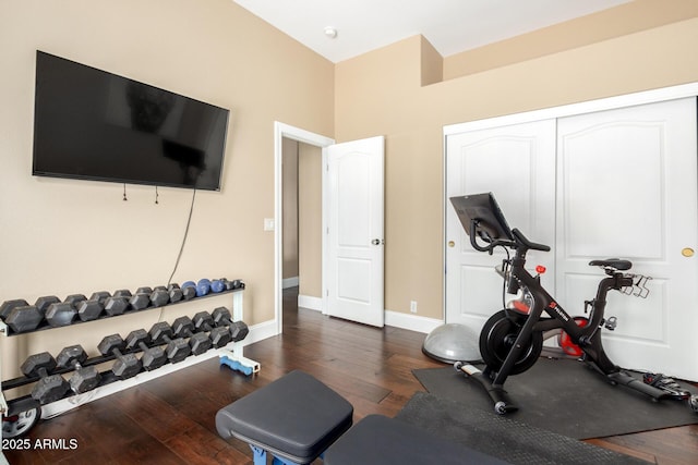 exercise area with dark wood-type flooring and baseboards
