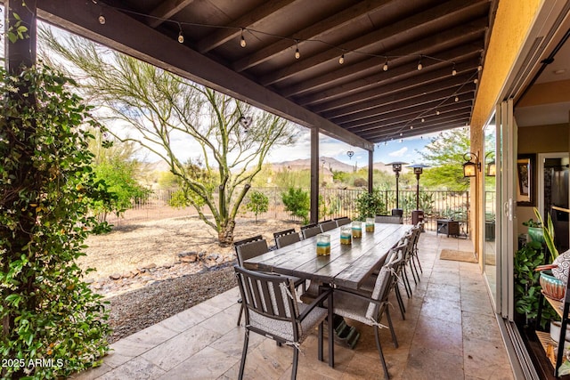 view of patio / terrace featuring fence, outdoor dining space, and a mountain view