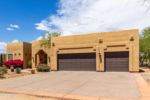 southwest-style home with a garage, stucco siding, and driveway
