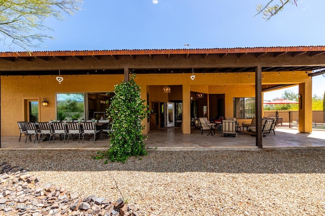 back of property with an outdoor living space, metal roof, fence, a patio, and stucco siding