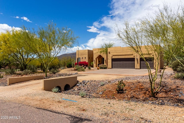 adobe home with a garage, stucco siding, and driveway