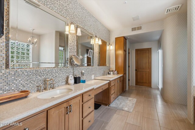 bathroom featuring tile patterned flooring, vanity, an inviting chandelier, and backsplash