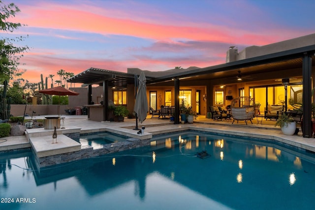 pool at dusk with an in ground hot tub, a pergola, and a patio area