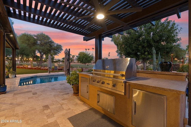 patio terrace at dusk featuring a pergola, an outdoor kitchen, and a grill