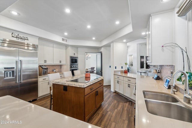 kitchen featuring white cabinetry, built in appliances, sink, and decorative backsplash