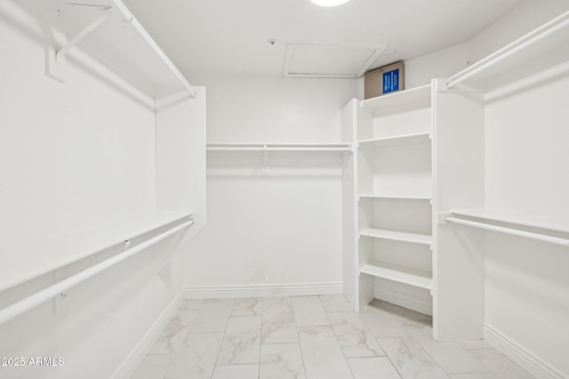 spacious closet featuring marble finish floor and attic access