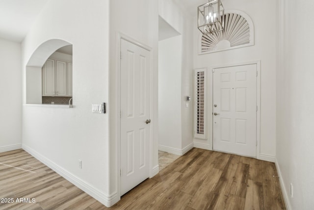 foyer entrance with a notable chandelier, baseboards, and wood finished floors