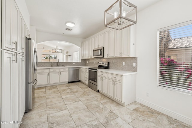 kitchen featuring visible vents, appliances with stainless steel finishes, hanging light fixtures, light countertops, and a sink