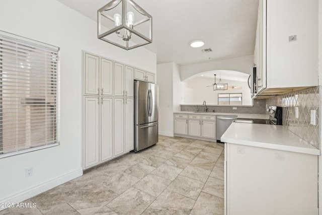 kitchen with light countertops, hanging light fixtures, an inviting chandelier, appliances with stainless steel finishes, and white cabinets