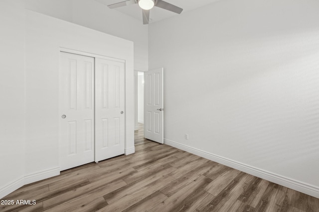 unfurnished bedroom with light wood-type flooring, a ceiling fan, baseboards, and a closet