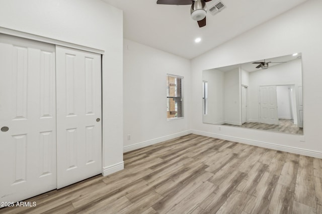 unfurnished bedroom with lofted ceiling, light wood-type flooring, visible vents, and baseboards