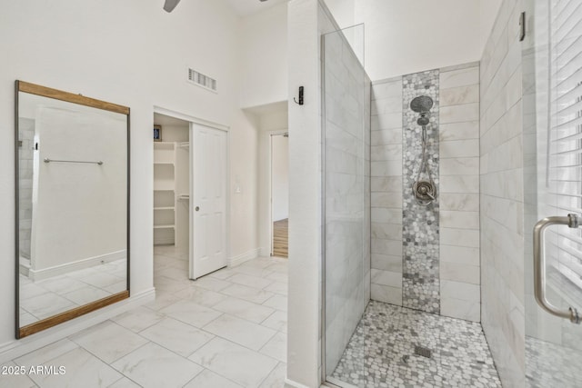 bathroom featuring a stall shower, baseboards, visible vents, a ceiling fan, and a walk in closet