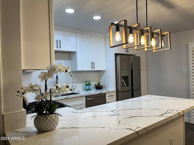 kitchen with dark hardwood / wood-style flooring, light stone counters, stainless steel appliances, decorative light fixtures, and white cabinets