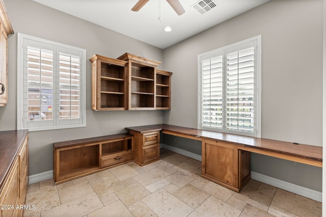 unfurnished office with ceiling fan and built in desk