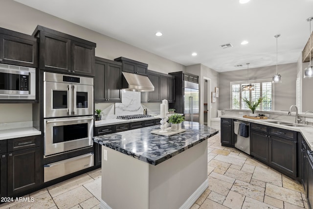 kitchen featuring decorative backsplash, dark stone counters, sink, built in appliances, and hanging light fixtures