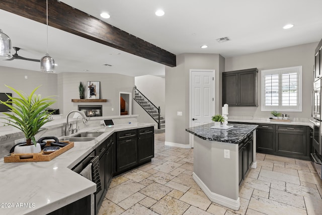 kitchen with pendant lighting, a center island, sink, dark stone countertops, and beamed ceiling