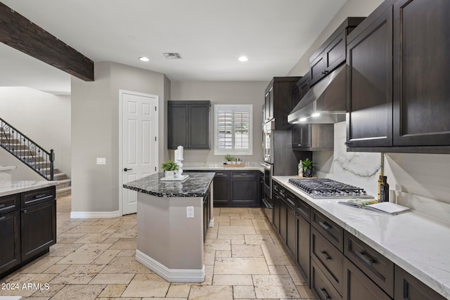 kitchen featuring dark brown cabinetry, light stone counters, and stainless steel appliances