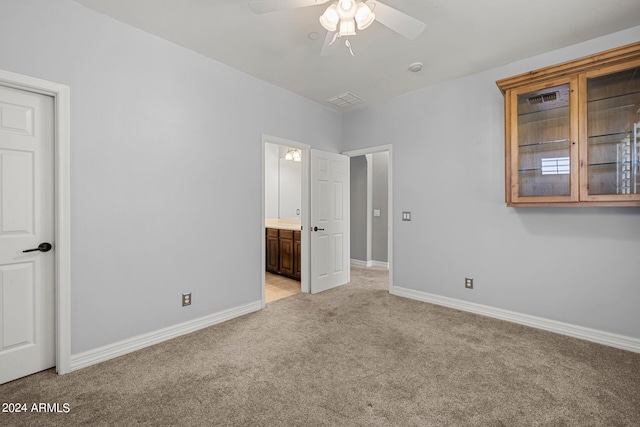 unfurnished bedroom with ceiling fan, ensuite bathroom, and light carpet