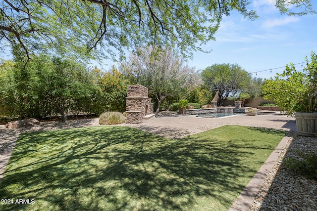 view of yard with an outdoor stone fireplace and a patio