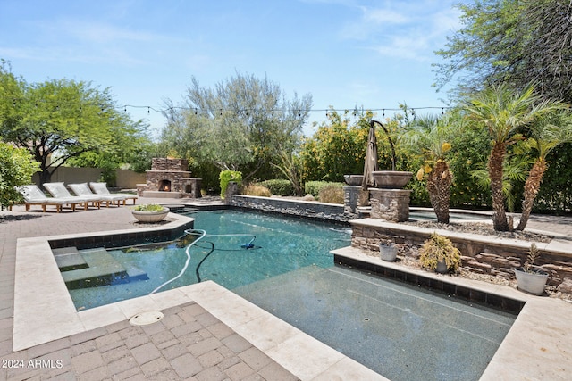 view of pool with an outdoor stone fireplace and a patio area