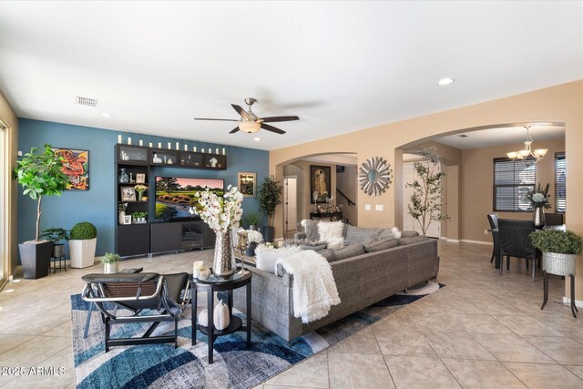 living room with ceiling fan with notable chandelier and light tile patterned floors